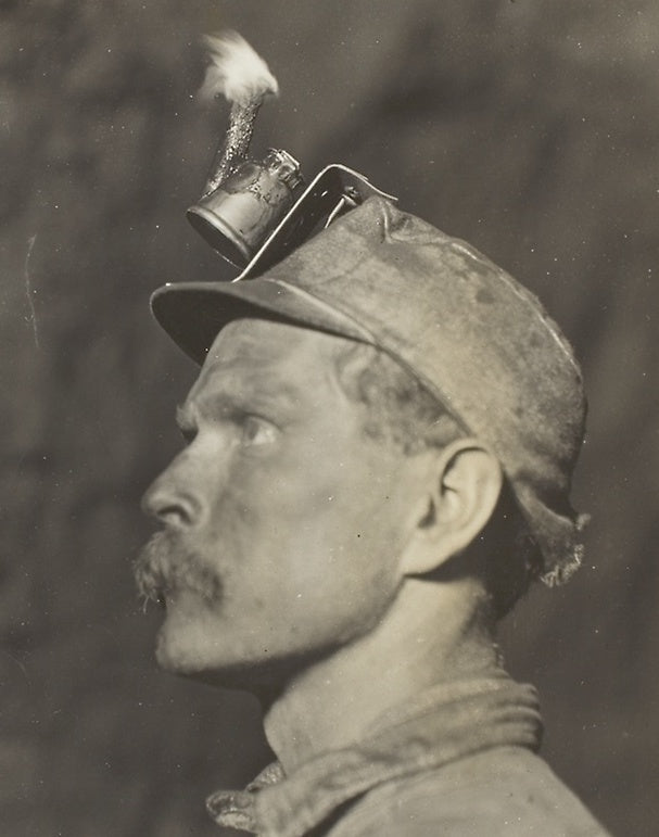 A Lewis Hine photograph of a coal miner's cap fitted with a lit carbide lamp, early 1900s